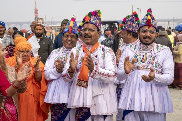 Hindu devotees wearing the ceremonial costume of the Kathiawar region in Gujarat state, sing hymns at the confluence of the Ganges, the Yamuna and the mythical Saraswati rivers, a day before the official beginning of the 45-day-long Maha Kumbh festival, in Prayagraj, India, Sunday, Jan. 12, 2025. (AP Photo/Ashwini Bhatia)